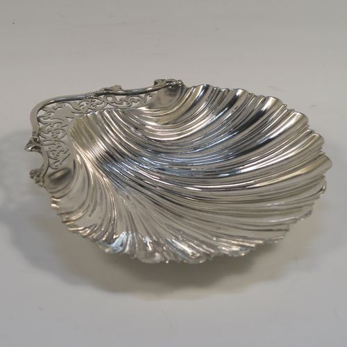 A very pretty Antique Edwardian Sterling Silver butter shell dish, having a hand-chased scalloped body, a hand-pierced handle with scroll-work and applied foliate border, and all sitting on three ball feet. This beautiful antique silver butter shell was made by Thomas Latham & Ernest Morton of Chester in 1902. The dimensions of this fine hand-made antique silver butter dish shell are length 14 cms (5.5 inches), width 12.5 cms (5 inches), and it weighs approx 75g (2.4 troy ounces).  