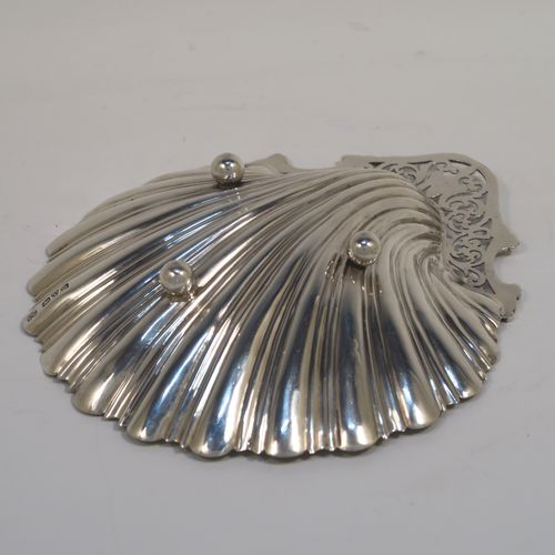 A very pretty Antique Edwardian Sterling Silver butter shell dish, having a hand-chased scalloped body, a hand-pierced handle with scroll-work and applied foliate border, and all sitting on three ball feet. This beautiful antique silver butter shell was made by Thomas Latham & Ernest Morton of Chester in 1902. The dimensions of this fine hand-made antique silver butter dish shell are length 14 cms (5.5 inches), width 12.5 cms (5 inches), and it weighs approx 75g (2.4 troy ounces).  