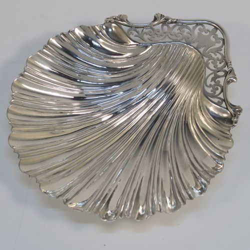 A very pretty Antique Edwardian Sterling Silver butter shell dish, having a hand-chased scalloped body, a hand-pierced handle with scroll-work and applied foliate border, and all sitting on three ball feet. This beautiful antique silver butter shell was made by Thomas Latham & Ernest Morton of Chester in 1902. The dimensions of this fine hand-made antique silver butter dish shell are length 14 cms (5.5 inches), width 12.5 cms (5 inches), and it weighs approx 75g (2.4 troy ounces).  