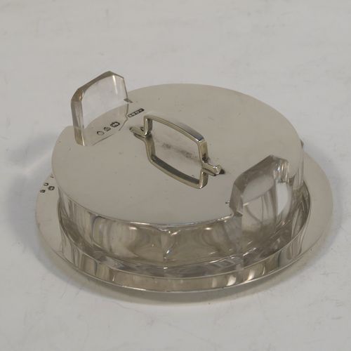 A very unusual Antique Victorian Sterling Silver and crystal butter dish and cover in an Arts and Crafts style, having a panelled crystal body with two side-handles, a lift-off plain round cover with handle, and all sitting in a plain round plate with a flat base. This elegant antique silver butter dish and cover was made by John Grinsell of London in 1893. The dimensions of this fine hand-made antique silver butter dish are diameter 8.5 cms (3.3 inches), height width 11 cms (4.25 inches), height 3.5 cms (1.3 inch), with a total weight of approx. 60g (2 troy ounces).   