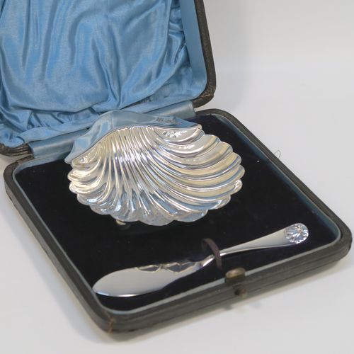 A very handsome Antique Victorian Sterling Silver butter shell and original butter knife, the shell having a hand-chased scalloped body, and sitting on three ball feet, the butter knife in the Old English Shell pattern, and all in their original blue satin and velvet-lined presentation box. Made by John & William Deakin of Sheffield in 1896. The dimensions of this fine hand-made antique silver butter dish and knife are length of dish 10 cms (4 inches), width 8.5 cms (3.25 inches), length of knife 10.5 cms (4.25 inches), and they weigh a total of approx 47g (1.5 troy ounces).   