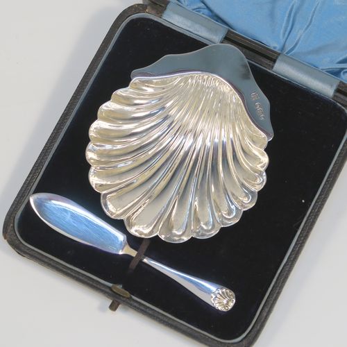 A very handsome Antique Victorian Sterling Silver butter shell and original butter knife, the shell having a hand-chased scalloped body, and sitting on three ball feet, the butter knife in the Old English Shell pattern, and all in their original blue satin and velvet-lined presentation box. Made by John & William Deakin of Sheffield in 1896. The dimensions of this fine hand-made antique silver butter dish and knife are length of dish 10 cms (4 inches), width 8.5 cms (3.25 inches), length of knife 10.5 cms (4.25 inches), and they weigh a total of approx 47g (1.5 troy ounces).   