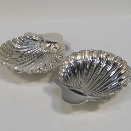 A pretty Antique Victorian Sterling Silver pair of butter shells, having hand-chased scalloped bodies, plain shaped thumb-pieces, and both sitting on three ball feet. These beautiful silver shell butter dishes were made by the Atkins Brothers of Sheffield in 1895. The dimensions of these fine hand-made antique silver butter dishes are length 12.5 cms (5 inches), width 10 cms (4 inches), and they have a total weight of approx. 124g (4 troy ounces).   