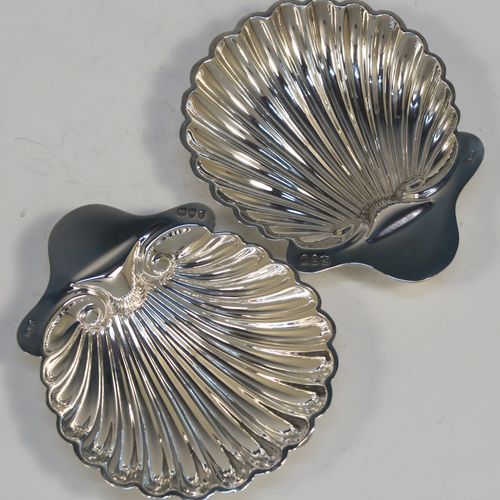 A pretty Antique Victorian Sterling Silver pair of butter shells, having hand-chased scalloped bodies, plain shaped thumb-pieces, and both sitting on three ball feet. These beautiful silver shell butter dishes were made by the Atkins Brothers of Sheffield in 1895. The dimensions of these fine hand-made antique silver butter dishes are length 12.5 cms (5 inches), width 10 cms (4 inches), and they have a total weight of approx. 124g (4 troy ounces).   