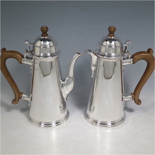 A Sterling Silver pair of cafe-au-lait pots, in a George I style, having very plain round bodies with tapering sides, brown wooden scroll handles, domed hinged lids with wooden finials, and sitting on collet feet. Made by Mappin & Webb of London in 1930. The dimensions of this fine pair of hand-made silver cafe-au-lait pots are height 20 cms (8 inches), length of coffee pot 16 cms (6.25 inches), and they weigh approx 839g (27 troy ounces).    