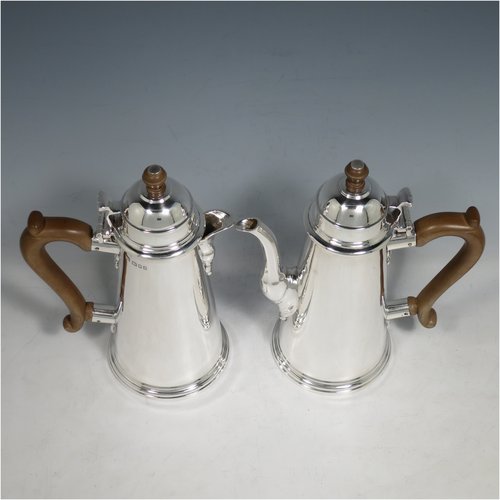 A Sterling Silver pair of cafe-au-lait pots, in a George I style, having very plain round bodies with tapering sides, brown wooden scroll handles, domed hinged lids with wooden finials, and sitting on collet feet. Made by Mappin & Webb of London in 1930. The dimensions of this fine pair of hand-made silver cafe-au-lait pots are height 20 cms (8 inches), length of coffee pot 16 cms (6.25 inches), and they weigh approx 839g (27 troy ounces).    