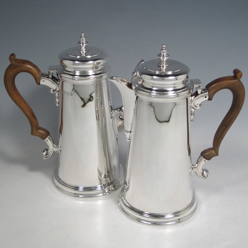 Sterling silver pair of cafe-au-lait pots, in a George I style, having very plain round bodies with tapering sides, brown wooden scroll side-handles, cushioned hinged lids with silver finials, and sitting on flat bases. Made by C. J. Vander of London in 1936. The dimensions of this fine pair of silver cafe-au-lait pots are height 20 cms (8 inches), length of coffee pot 19 cms (7.5 inches), and they weigh approx 930g (30 troy ounces).    