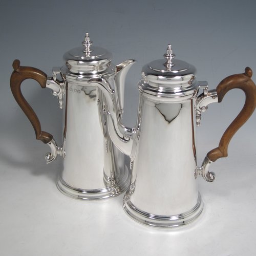 Sterling silver pair of cafe-au-lait pots, in a George I style, having very plain round bodies with tapering sides, brown wooden scroll side-handles, cushioned hinged lids with silver finials, and sitting on flat bases. Made by C. J. Vander of London in 1936. The dimensions of this fine pair of silver cafe-au-lait pots are height 20 cms (8 inches), length of coffee pot 19 cms (7.5 inches), and they weigh approx 930g (30 troy ounces).    