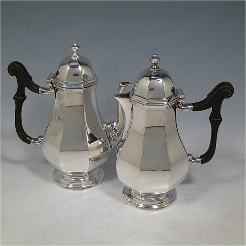 An Antique Sterling Silver pair of cafe-au-lait pots, having plain panelled and bellied bodies, with black wooden scroll handles, hinged and panelled domed lids with cast finials, and sitting on pedestal feet. Made by the Goldsmiths & Silversmiths of London in 1913. The dimensions of this fine hand-made pair of antique sterling silver cafe-au-lait pots are height 17 cms (6.75 inches), length of coffee pot 14.5 cms (5.75 inches), and they weigh approx. 495g (16 troy ounces).    