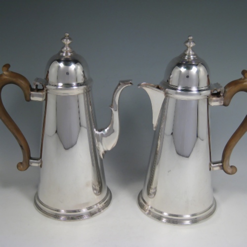 Silver-plated pair of cafe-au-lait serving pots in the George I style with domed hinged lids, straight sided, and wooden handles. Made by Aspreys of London in ca. 1950. Height 25.5 cms (10 inches), length of coffee pot 19 cms (7.5 inches).