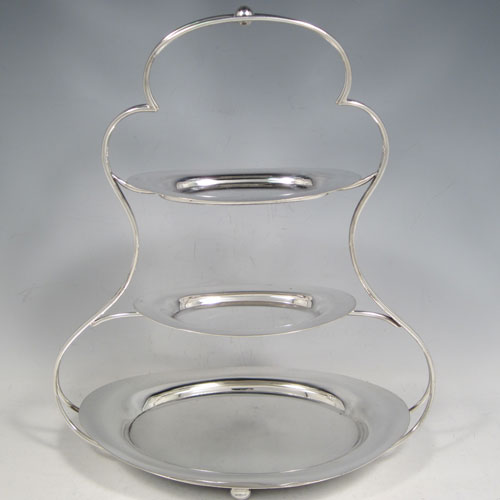 Antique Edwardian Art Nouveau silver plated three-tier cake stand, having a suite of three removable oval plates, sitting within a shaped frame with four cushion feet. Made by George Unite of Birmingham in ca. 1900. The dimensions of this fine hand-made silver-plated cake stand are height 29 cms (11.5 inches), width at base 24 cms (9.5 inches), width of largest plate 21.5 cms (8.5 inches), width of smaller plates 13.5 cms (5.25 inches).