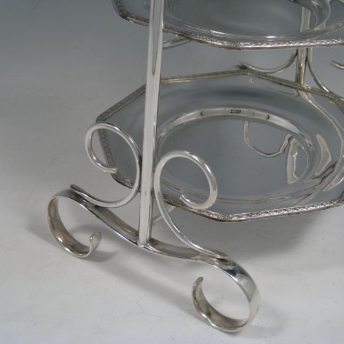 Antique Edwardian silver plated three-tier cake stand, having a graduated suite of three removable octagonal plates with applied leaf borders, sitting within a very pretty tapering frame with scroll-work handle and feet. Made by Frederick Atkins of Sheffield in ca. 1910. The dimensions of this fine hand-made silver-plated cake stand are height 38 cms (15 inches), width at base 22 cms (8.6 inches), width of largest plate 18 cms (7 inches), width of smallest plate 14 cms (5.5 inches).   