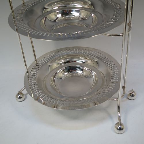 A pretty Antique Edwardian Silver Plated three-tier cake stand, having a suite of three removable round plates with pierced borders and fairly deep bowls, sitting within a very pretty wire-work frame with scroll-work handle and four ball feet. Made in ca. 1900. The dimensions of this fine hand-made antique silver-plated cake stand are height 49 cms (19.25 inches), width across feet at base 26 cms (10.25 inches), and diameter of plates are 21 cms (8.25 inches).  