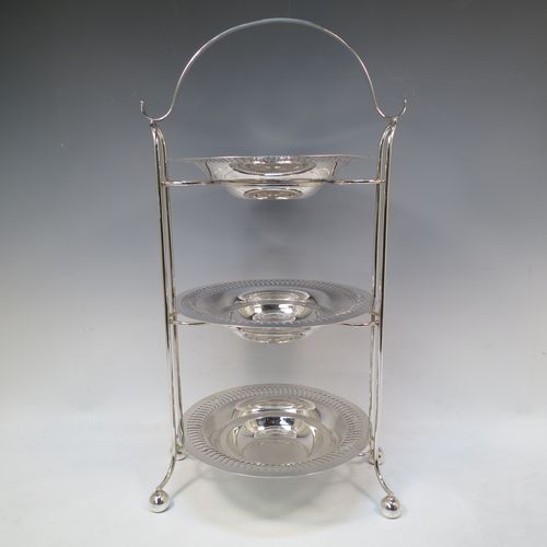 A pretty Antique Edwardian Silver Plated three-tier cake stand, having a suite of three removable round plates with pierced borders and fairly deep bowls, sitting within a very pretty wire-work frame with scroll-work handle and four ball feet. Made in ca. 1900. The dimensions of this fine hand-made antique silver-plated cake stand are height 49 cms (19.25 inches), width across feet at base 26 cms (10.25 inches), and diameter of plates are 21 cms (8.25 inches).  