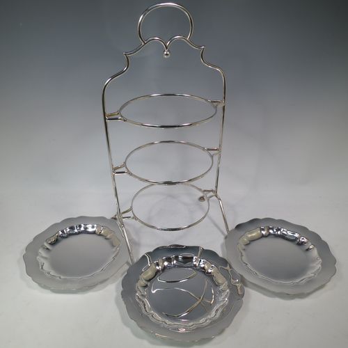 A pretty Antique Edwardian silver plated three-tier cake stand, having a suite of three plain removable plates with wavey-edged borders, sitting within a very pretty wire-work frame with scroll-work handle and four cast bun feet. Made in Sheffield in ca. 1910. The dimensions of this fine hand-made antique silver-plated cake stand are height 43 cms (17 inches), width at base 23 cms (9 inches), and diameter of plates 20 cms (8 inches).    