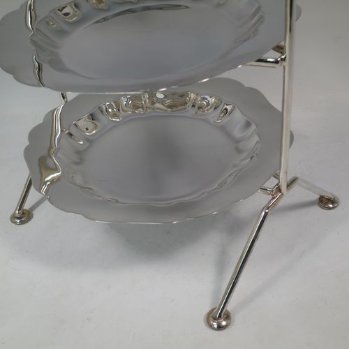 A pretty Antique Edwardian silver plated three-tier cake stand, having a suite of three plain removable plates with wavey-edged borders, sitting within a very pretty wire-work frame with scroll-work handle and four cast bun feet. Made in Sheffield in ca. 1910. The dimensions of this fine hand-made antique silver-plated cake stand are height 43 cms (17 inches), width at base 23 cms (9 inches), and diameter of plates 20 cms (8 inches).    