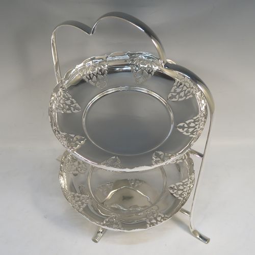 A pretty Antique Edwardian silver-plated cake stand, having two removable scalloped plates with round bodies and hand-pierced floral decoration. All sitting in a plain wire-work frame which in-turn sits on four scroll feet. This beautiful antique silver-plated cake stand was made in Sheffield ca. 1910. The dimensions of this fine hand-made antique silver-plated cake stand are height 36 cms (14.25 inches), width 30 cms (11.75 inches), and the plates are 21 cms (8.25 inches) square.   