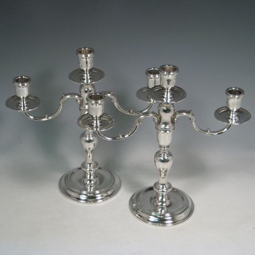 Sterling silver pair of three-light candelabra, having plain round baluster bodies, removable scroll arms, and with drip pans below the nozzles. Made by C. J. Vander of London in 1971. Height 30 cms (11.75 inches), spread across arms 30.5 cms (12 inches). Total weight approx. 1,583g (51 troy ounces). Please note that these candelabra are not filled.