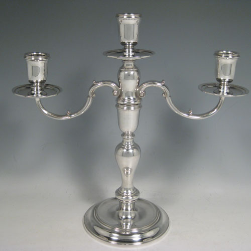 Sterling silver pair of three-light candelabra, having plain round baluster bodies, removable scroll arms, and with drip pans below the nozzles. Made by C. J. Vander of London in 1971. Height 30 cms (11.75 inches), spread across arms 30.5 cms (12 inches). Total weight approx. 1,583g (51 troy ounces). Please note that these candelabra are not filled.