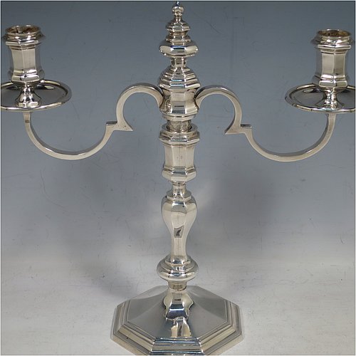 A Sterling Silver cast pair of George II style two-light candelabra, having octagonal panelled and baluster style bodies with reeded borders, removable scroll arms with nozzles and drip pans, and a central finial. Made in Birmingham in 1974. The dimensions of this fine hand-made pair of silver candelabra are height 24 cms (9.5 inches), spread across arms 25.5 cms (10 inches), and with a total weight of approx. 1,418g (45.7 troy ounces). Please note that these candelabra are all cast and not filled.   