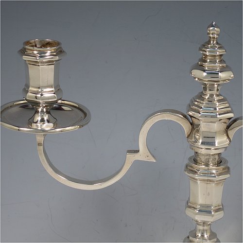 A Sterling Silver cast pair of George II style two-light candelabra, having octagonal panelled and baluster style bodies with reeded borders, removable scroll arms with nozzles and drip pans, and a central finial. Made in Birmingham in 1974. The dimensions of this fine hand-made pair of silver candelabra are height 24 cms (9.5 inches), spread across arms 25.5 cms (10 inches), and with a total weight of approx. 1,418g (45.7 troy ounces). Please note that these candelabra are all cast and not filled.   