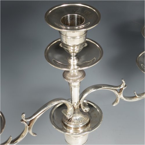 An Antique Georgian / Victorian Sterling Silver pair of candelabra in a Neoclassical style, having removable arms with three lights, fluted and reed-banded columns with round bases, cast scroll-shaped arms, capitals with reeded decoration, removable nozzles with drip pans, and reed-edged borders. The candelabra bases are made by Matthew Boulton of Birmingham in 1795, whilst the branches are made by James Garrard of London in 1883. The dimensions of this fine hand-made pair of silver candelabra are height 41.5 cms (16.3 inches), and spread across arms 31.5 cms (12.3 inches). Please note that these are crested on the bases and nozzles.