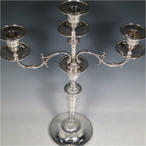 An Antique Georgian / Victorian Sterling Silver pair of candelabra in a Neoclassical style, having removable arms with three lights, fluted and reed-banded columns with round bases, cast scroll-shaped arms, capitals with reeded decoration, removable nozzles with drip pans, and reed-edged borders. The candelabra bases are made by Matthew Boulton of Birmingham in 1795, whilst the branches are made by James Garrard of London in 1883. The dimensions of this fine hand-made pair of silver candelabra are height 41.5 cms (16.3 inches), and spread across arms 31.5 cms (12.3 inches). Please note that these are crested on the bases and nozzles.