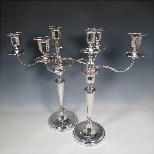 An Antique Edwardian Sterling Silver pair of candelabra in a round plain panelled style, having removable arms with three lights, panelled columns with round bases, double swirl panelled arms, capitals with removable nozzles and drip pans, and reed-edged borders. Made by Goldsmiths & Silversmiths of London in 1905. The dimensions of this fine hand-made pair of silver candelabra are height 44.5 cms (17.5 inches), and spread across arms 39.5 cms (15.5 inches).   