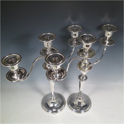 An Antique Edwardian Sterling Silver pair of candelabra in a round plain panelled style, having removable arms with three lights, panelled columns with round bases, double swirl panelled arms, capitals with removable nozzles and drip pans, and reed-edged borders. Made by Goldsmiths & Silversmiths of London in 1905. The dimensions of this fine hand-made pair of silver candelabra are height 44.5 cms (17.5 inches), and spread across arms 39.5 cms (15.5 inches).   