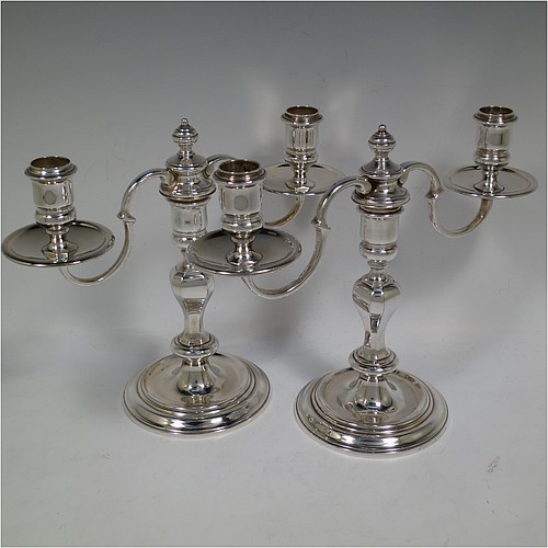 A very handsome Silver Plated cast pair of George II style two-light candelabra, having octagonal panelled and round baluster style bodies with reeded borders, removable scroll arms with two-lights and drip pans, and a central finial. Made in circa 1930. The dimensions of this fine hand-made pair of silver-plated candelabra are height 19 cms (7.5 inches), and spread across arms 25.5 cms (10 inches).   