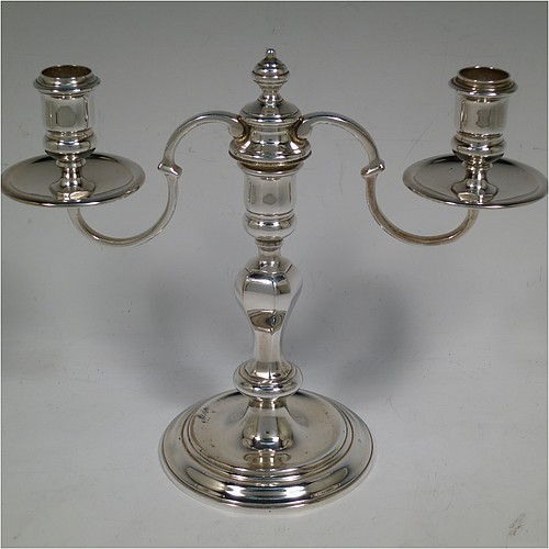 A very handsome Silver Plated cast pair of George II style two-light candelabra, having octagonal panelled and round baluster style bodies with reeded borders, removable scroll arms with two-lights and drip pans, and a central finial. Made in circa 1930. The dimensions of this fine hand-made pair of silver-plated candelabra are height 19 cms (7.5 inches), and spread across arms 25.5 cms (10 inches).   