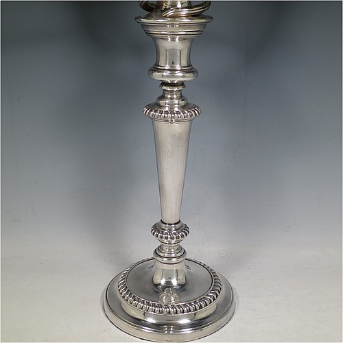 An Antique Georgian Old Sheffield Silver Plated pair of candelabra in a very elegant Regency style, having removable arms with three lights, with plain round baluster columns and bases, and plain reeded double swirl arms, removable nozzles with drip pans, and gadroon edged borders. Made in ca. 1815. The dimensions of this fine hand-made pair of Old Sheffield three-light candelabra are height 49 cms (19.25 inches), and spread across arms 39.5 cms (15.5 inches). Please note that the bases are crested.