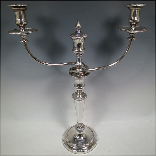 An Antique Georgian Old Sheffield Silver Plated pair of candelabra in a very elegant Regency style, having removable arms with three lights, with plain round baluster columns and bases, and plain reeded double swirl arms, removable nozzles with drip pans, and gadroon edged borders. Made in ca. 1810. The dimensions of this fine hand-made pair of Old Sheffield three-light candelabra are height 51 cms (20 inches), and spread across arms 40 cms (15.75 inches). Please note that these can be combined into a single five-light candelabrum if required.   