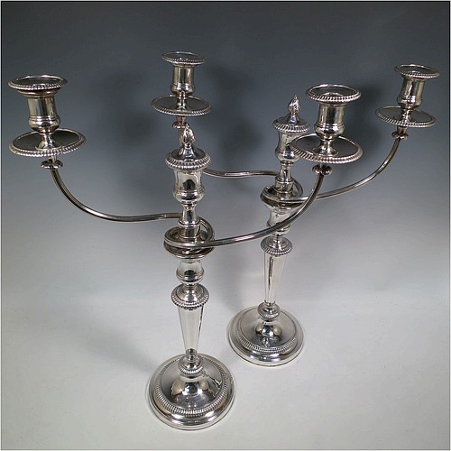 An Antique Georgian Old Sheffield Silver Plated pair of candelabra in a very elegant Regency style, having removable arms with three lights, with plain round baluster columns and bases, and plain reeded double swirl arms, removable nozzles with drip pans, and gadroon edged borders. Made in ca. 1810. The dimensions of this fine hand-made pair of Old Sheffield three-light candelabra are height 51 cms (20 inches), and spread across arms 40 cms (15.75 inches). Please note that these can be combined into a single five-light candelabrum if required.   