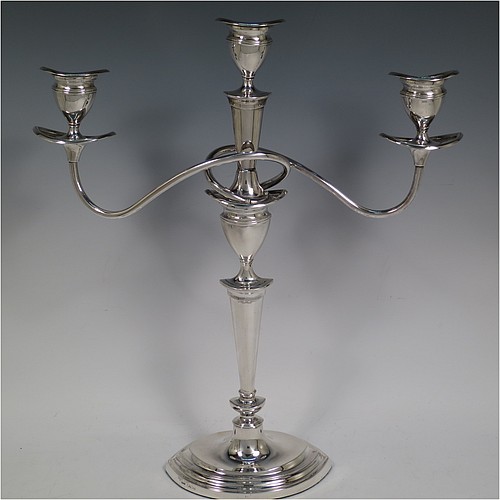 A very pretty Sterling Silver pair of candelabra in a Neoclassical boat-shaped style, having removable arms with three lights, plain and reed-banded columns with pointed oval bases, with plain scroll-shaped arms, capitals with reeded decoration, removable nozzles with drip pans, and reed-edged borders. Made by Mappin and Webb of Sheffield in 1938. The dimensions of this fine hand-made pair of silver candelabra are height 36.5 cms (14.3 inches), and spread across arms 32.5 cms (12.75 inches).    