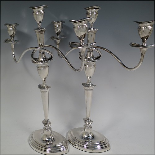 A very pretty Sterling Silver pair of candelabra in a Neoclassical boat-shaped style, having removable arms with three lights, plain and reed-banded columns with pointed oval bases, with plain scroll-shaped arms, capitals with reeded decoration, removable nozzles with drip pans, and reed-edged borders. Made by Mappin and Webb of Sheffield in 1938. The dimensions of this fine hand-made pair of silver candelabra are height 36.5 cms (14.3 inches), and spread across arms 32.5 cms (12.75 inches).    