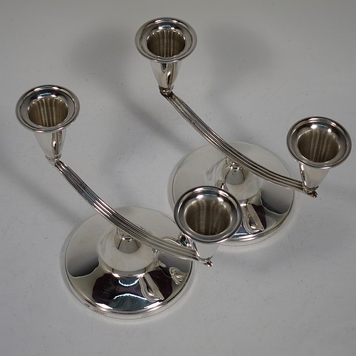 An unusual Sterling Silver pair of small two-light candelabra, having round bases with a cast reeded arms, with two attached plain round candle-holders. Made by Elkington and Co., of Birmingham in 1989. The dimensions of this fine hand-made pair of silver candelabra are height 11 cms (4.25 inches), and spread across arms 15 cms (6 inches).    