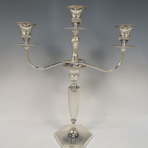 A very elegant pair of three-light Silver Plated Art Deco style candelabra, having plain hexagonal bases with an applied lower bead border, a plain panelled column with tapering sides, with removable swirl hexagonal cross-section arms, and matching capitals with removable nozzles and bead-edged borders. Made by Hawksworth and Eyre of Sheffield in ca. 1930. The dimensions of this fine hand-made pair silver-plated  Art Deco candelabra are height 40 cms (15.75 inches), and spread across arms 37 cms (14.5 inches).