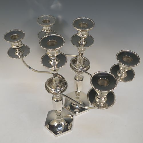 A very elegant pair of three-light Silver Plated Art Deco style candelabra, having plain hexagonal bases with an applied lower bead border, a plain panelled column with tapering sides, with removable swirl hexagonal cross-section arms, and matching capitals with removable nozzles and bead-edged borders. Made by Hawksworth and Eyre of Sheffield in ca. 1930. The dimensions of this fine hand-made pair silver-plated  Art Deco candelabra are height 40 cms (15.75 inches), and spread across arms 37 cms (14.5 inches).