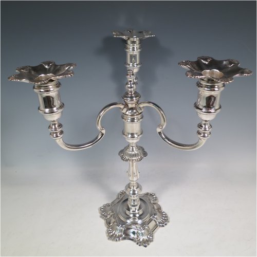 A Sterling Silver cast pair of George II style three-light candelabra, having round baluster bodies with six-shell borders, removable scroll arms with nozzles, and a central finial. Made by Mappin & Webb of Birmingham in 1969. The dimensions of this fine hand-made pair of silver candelabra are height 30 cms (11.75 inches), spread across arms 25 cms (9.75 inches), and with a total weight of approx. 2,538g (82 troy ounces). Please note that these candelabra are all cast and not filled.