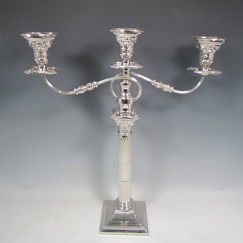 A Sterling silver pair of candelabra in the Corinthian style, having removable arms with three lights, fluted columns with stepped square bases, double swirl reeded arms, acanthus leaf capitals, removable nozzles with drip pans, and bead-edged borders. Made in London in 1933. The dimensions of this fine hand-made silver pair of candelabra are height 49 cms (19.25 inches), and spread across arms 40 cms (15.75 inches).   