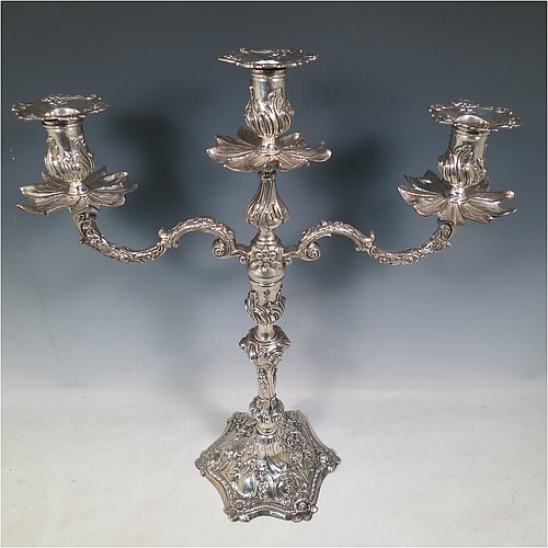 Antique Georgian sterling silver pair of cast Rococo style three-light candelabra, having hand-chased floral decoration with roses and anthemion leaves, removable arms, unusual leaf drip pans, and removable nozzles. Made by William Cafe of London in 1768. Height 45 cms (17.75 inches), spread across arms 39.5 cms (15.5 inches). Total weight approx. 3,705g (119.5 troy ounces).