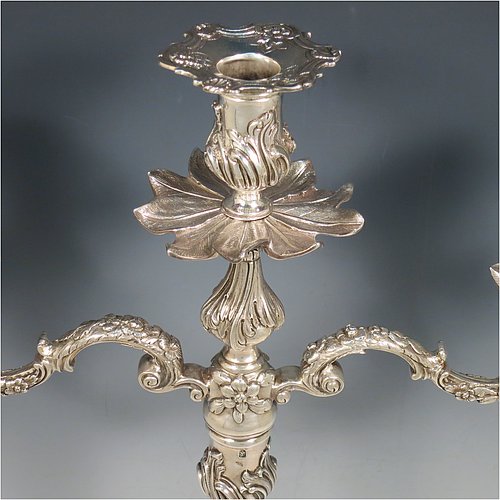 Antique Georgian sterling silver pair of cast Rococo style three-light candelabra, having hand-chased floral decoration with roses and anthemion leaves, removable arms, unusual leaf drip pans, and removable nozzles. Made by William Cafe of London in 1768. Height 45 cms (17.75 inches), spread across arms 39.5 cms (15.5 inches). Total weight approx. 3,705g (119.5 troy ounces).