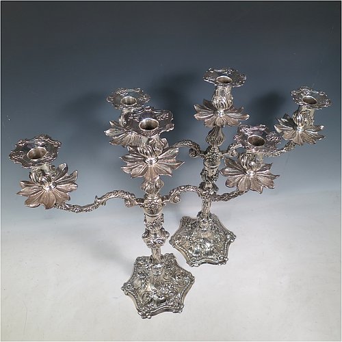 Antique Georgian sterling silver pair of cast Rococo style three-light candelabra, having hand-chased floral decoration with roses and anthemion leaves, removable arms, unusual leaf drip pans, and removable nozzles. Made by William Cafe of London in 1768. Height 45 cms (17.75 inches), spread across arms 39.5 cms (15.5 inches). Total weight approx. 3,705g (119.5 troy ounces).