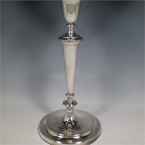 An Antique Georgian Old Sheffield Silver Plated pair of candelabra in a very elegant Neoclassical style, having removable arms with two lights and a central removable urn-shaped finial, with plain round baluster columns and bases, and plain double swirl arms, removable nozzles with drip pans, and reed-edged borders. Made in ca. 1790. The dimensions of this fine hand-made pair of Old Sheffield two-light candelabra are height 44 cms (17.3 inches), and spread across arms 36 cms (14 inches).    