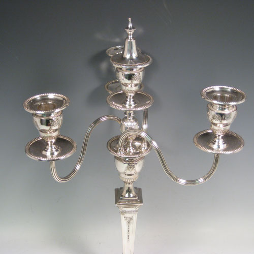    Antique Victorian sterling silver and silver-plated pair of four-light candelabra, having square bases and collumns with neoclassical style chased work, removable arms with drip pans, nozzles, and extinguishers, all with beaded borders. Please note that the bases are sterling silver and the arms are silver-plate. Made by J.K. Bembridge of Sheffield in 1884. Height 47 cms (18.5 inches), spread across arms 27 cms (10.5 inches).