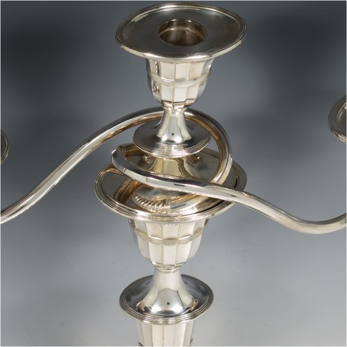 An Antique Victorian Silver Plated pair of candelabra in a Neoclassical style, having removable arms with three lights, fluted columns with oval bases, double swirl and panelled arms, capitals with fluted and reeded decoration, removable nozzles with drip pans, and reed-edged borders. Made by Hawksworth & Eyres in ca. 1900. The dimensions of this fine hand-made pair of silver-plated candelabra are height 37.5 cms (14.75 inches), and spread across arms 32 cms (12.5 inches).   