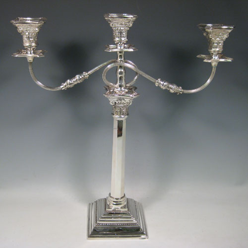 A Sterling silver single candelabrum, having three lights in a Corinthian style with a stepped square base, plain octagonal column, double swirl reeded arms, acanthus leaf capitals, removable nozzles with drip pans, and bead-edged borders. Made in London in 1957. The dimensions of this fine hand-made silver single candelabrum are height 43 cms (17 inches), and spread across arms 40 cms (15.75 inches).   