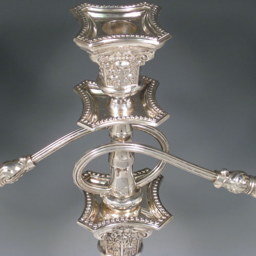 A Sterling silver single candelabrum, having three lights in a Corinthian style with a stepped square base, plain octagonal column, double swirl reeded arms, acanthus leaf capitals, removable nozzles with drip pans, and bead-edged borders. Made in London in 1957. The dimensions of this fine hand-made silver single candelabrum are height 43 cms (17 inches), and spread across arms 40 cms (15.75 inches).   