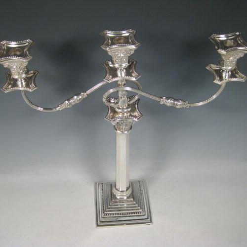 A Sterling silver single candelabrum, having three lights in a Corinthian style with a stepped square base, plain octagonal column, double swirl reeded arms, acanthus leaf capitals, removable nozzles with drip pans, and bead-edged borders. Made in London in 1957. The dimensions of this fine hand-made silver single candelabrum are height 43 cms (17 inches), and spread across arms 40 cms (15.75 inches).   